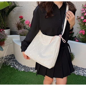 Close-up of white pleated PU leather crossbody bag with pink drawstring and bicolor strap