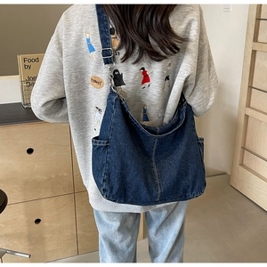 Detail van donkerblauwe denim hobo tas met contrasterende stiksels en verstelbare riem