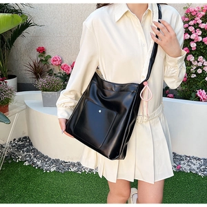Detail view of black PU leather crossbody bag with silver stud and pink decorative ribbon