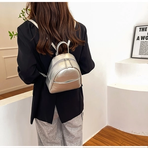 Silver metallic mini backpack worn by model in a stylish modern lifestyle setting
