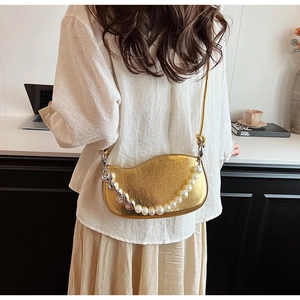 Détail d'un sac bandoulière doré en similicuir avec chaîne en perles et cœurs métal