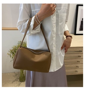 Detail of a brown lychee pattern PU leather tote bag with silver zipper on a model
