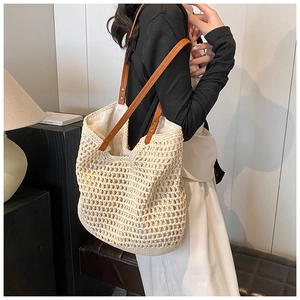 Detailed view of beige woven tote bag with brown faux leather straps and gold rivets
