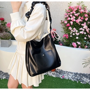 Close-up of black PU leather tote bag with unique ruffled strap and silver metal studs