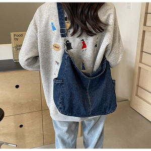 Detail van blauwe denim hobo tas met zijvak en metalen verstelbare gesp op band