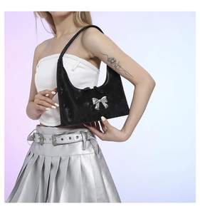 Close-up of black PU leather crescent bag featuring a metallic silver 3D bow accent