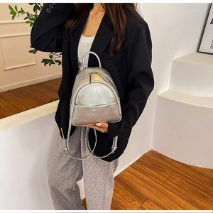 Silver metallic mini PU backpack shown on model in a modern minimalist fashion setting