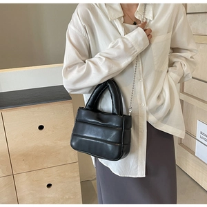 Detail of black quilted cloud bucket bag with silver bead chain strap and glossy finish