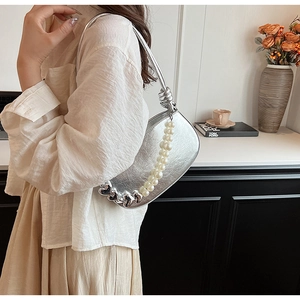 Détail du sac bandoulière argenté avec chaîne en perles et boucle en forme de cœur