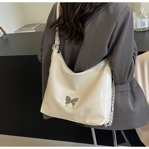 Detail showing creamy white glossy PU leather shoulder bag with metal butterfly buckle