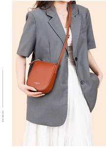 Detailed macro view of brown lychee grain leather texture and zipper on crossbody bag