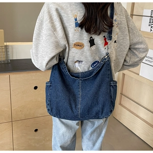 Detail van de donkerblauwe denim hobo tas met zijzakken en een brede schouderriem van stof