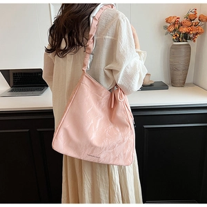 Detailed back view of a pink glossy pleated tote bag styled with a beige dress