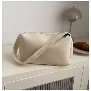 Minimalist beige pebble leather shoulder bag with wide strap and silver zipper closure