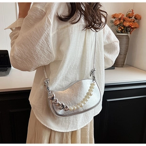 Sac demi-lune argenté chic avec chaîne en perles et cœurs porté à l'épaule