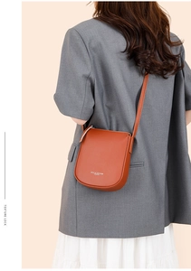 Close-up detail of caramel lychee grain leather crossbody bag with white brand logo