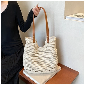 Detail of crochet knit tote bag with brown leather handles and diamond mesh texture