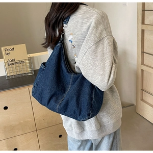 Detail van grote marineblauwe denim hobo tas met contrasterende stiksels en metalen gesp