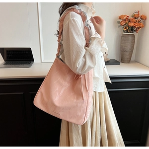 Close-up of pink pleated tote bag with ruffled shoulder strap and printed lettering
