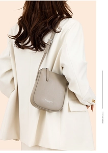 Detail of the pebble grain leather texture and adjustable strap on the grey crossbody bag