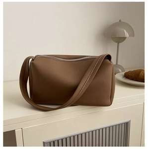 Minimalist brown lychee pattern PU leather handbag on a table with warm lighting
