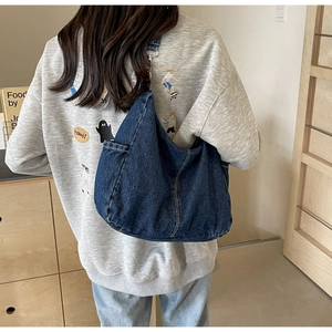 Detail van de donkerblauwe denim hobo tas met witte contraststiksels en zachte stoftextuur