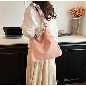 Detail of pink PU leather tote bag featuring ruched silver-lined straps and sleek logo print