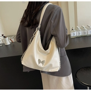 Close-up of a creamy white hobo bag with a silver butterfly accent and chain strap