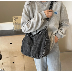 Detail van de zwarte gewassen denim hobo tas met bedrukte banden en zijzakken voor dames