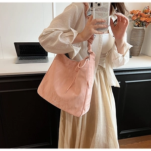 Detailed view of pink pleated PU shoulder bag with decorative knotted strap texture
