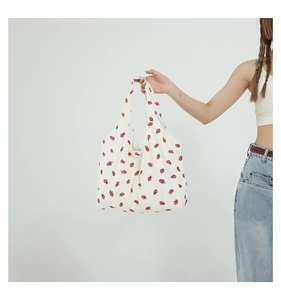 Detailansicht der cremefarbenen Canvas-Tasche mit Erdbeerdruck und Cord-Struktur