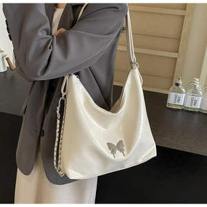Close-up of white glossy PU leather bag with silver butterfly and chain detail