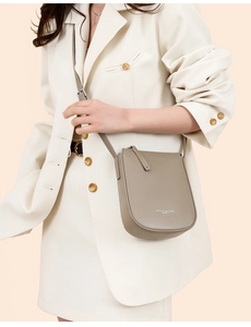 Detail of taupe leather crossbody bag with lychee texture and white logo lettering