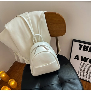 Minimalist white PU leather mini backpack with dual zippers in a cozy home setting