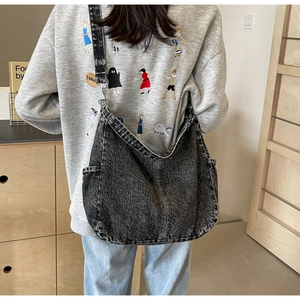 Macro-opname van de grote zwarte denim crossbody tas met waseffect en textuurdetails