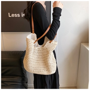 Detail view of cream crochet tote bag with brown faux leather strap in a home setting
