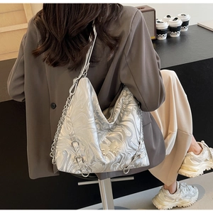 Silver metallic Y2K hobo bag with butterfly charm and chain strap detail on model