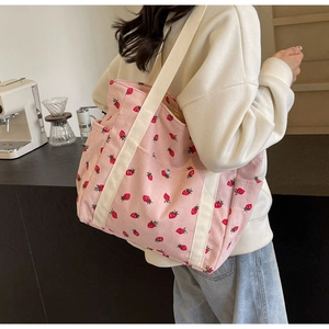 Vue détaillée du sac cabas en velours côtelé rose avec imprimé fraises et poche latérale