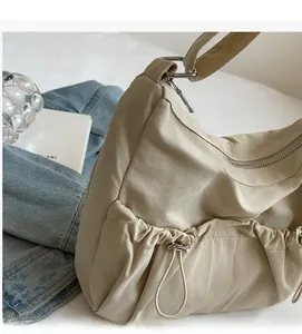Detailansicht der beigen Stofftasche mit Kordelzug-Seitentasche und silbernen Reißverschlüssen