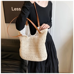 Detail of white woven tote bag with brown leather straps and metal rivets on model