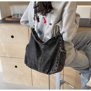 Detail van grijze gewassen denim hobo tas met verstelbare gesp op het model