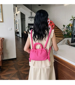 Back view of a quilted bright pink puffy backpack shown in a minimalist cafe setting