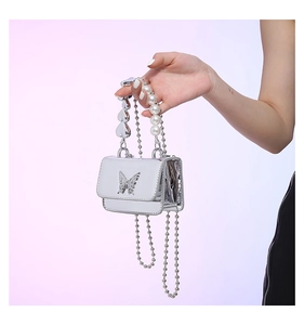 Detail view of silver mini bag with heart handle, pearl ring, and butterfly metal ornament