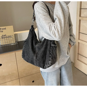 Detail van zwarte gewassen denim hobo tas met zijvakken en zilveren metalen gespen