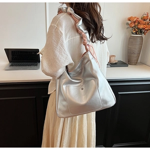 Detailed view of silver metallic PU leather tote bag with stylish ruffled shoulder straps