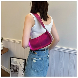 Détail du sac demi-lune rouge rose avec des clous argentés sur la bandoulière réglable