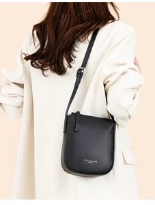 Close-up of black lychee grain leather crossbody bag with silver buckle and logo detail