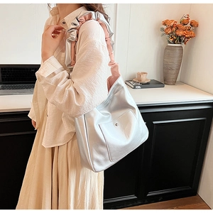 Detail of silver PU leather crossbody bag featuring a pink lined ruffle shoulder strap