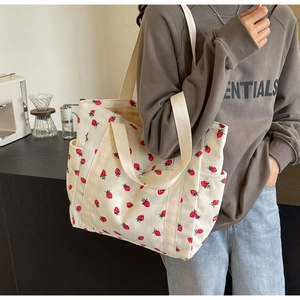 Détail du sac fourre-tout en toile à motif fraises avec poches latérales pratiques