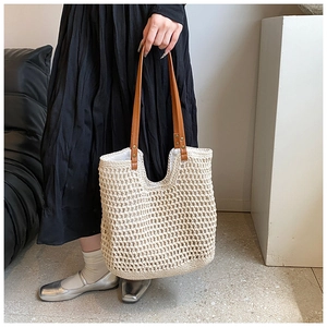 Detailed close-up of bohemian woven handbag with brown leather straps and metal rivets